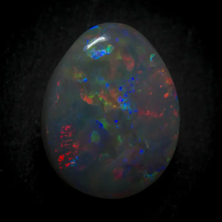 Opale naturelle australienne des mines de Lightning Ridge, larme sombre de 1,4 carats, polie sur une face, colorée sur toute sa surface et à diffractions dominantes rouges, bleues et vertes