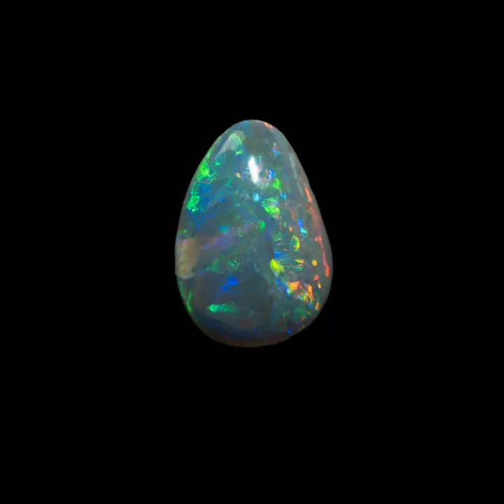 Opale naturelle australienne des mines de Lightning Ridge, cristal sombre en forme de larme de 0,6 carats à brillances majoritaires bleues, vertes, oranges et jaunes.