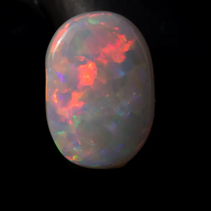 opale naturelle australienne des mines de Coober Pedy, ovale de 0,9 carat d'opale sombre presque de catégorie blanche à brillances multicolores majoritairement rouge et orange