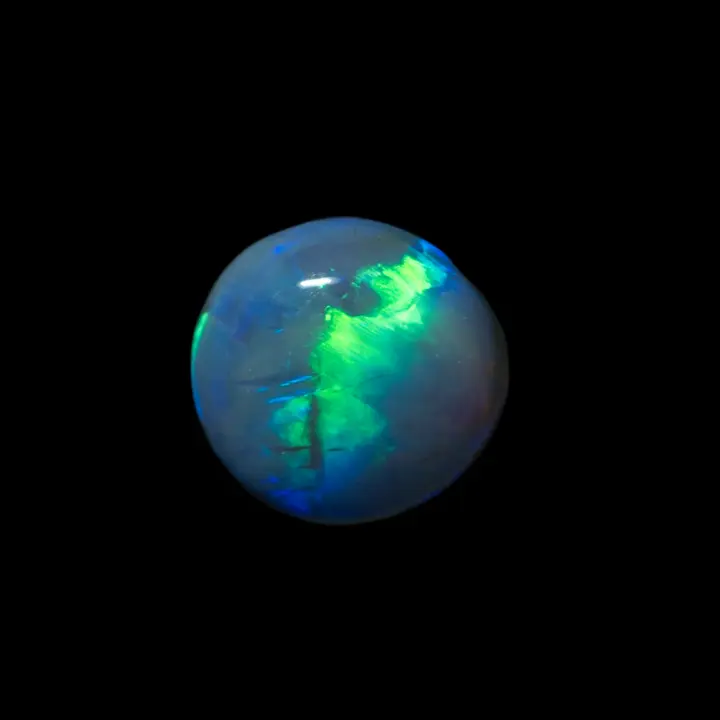 Opale naturelle australienne des mines de Lightning Ridge, demi sphère de 1,6 carat d'opale noire traversée d'un flash lumineux en ligne verte et bleue