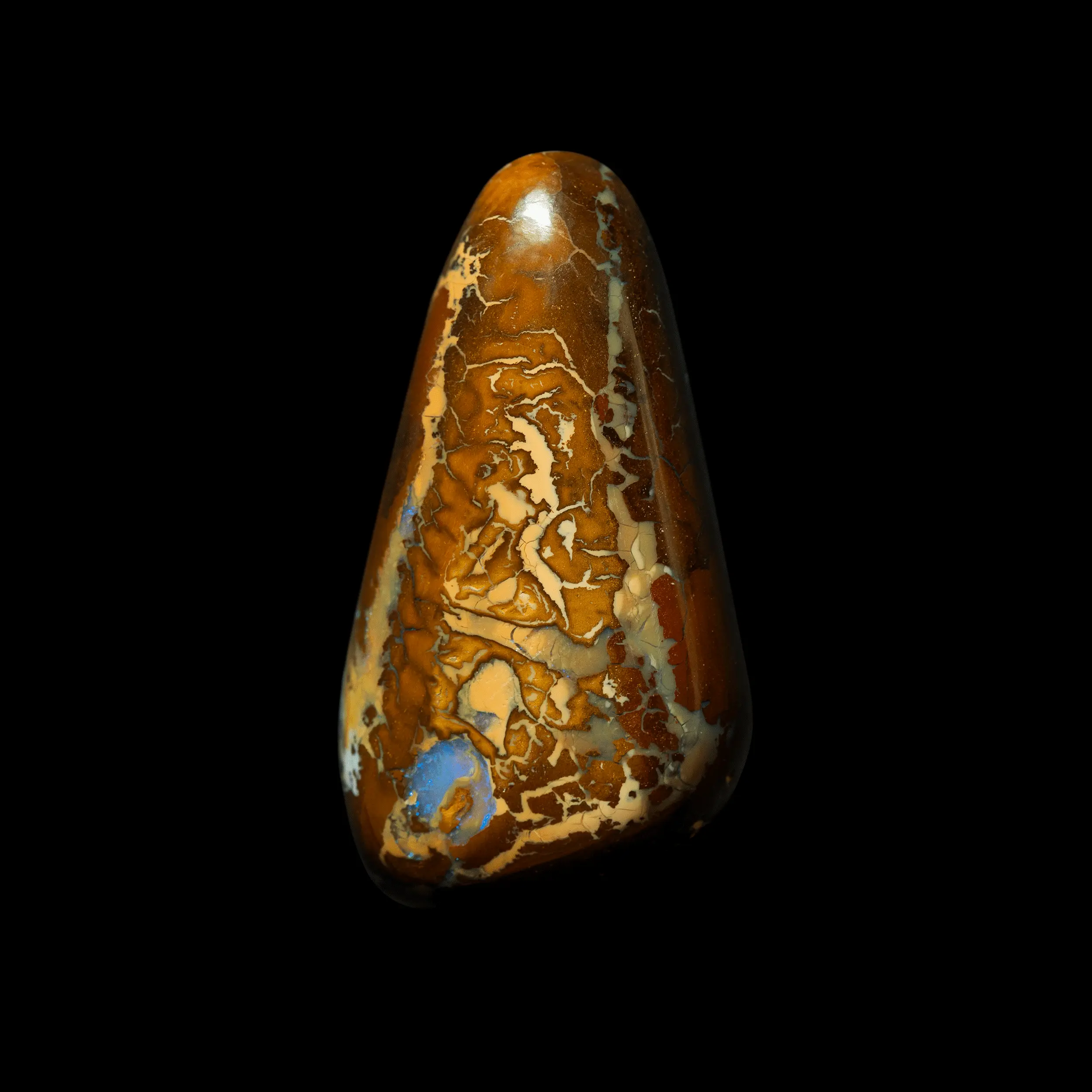Natural Australian opal from the Koroit mines, free-form near-triangle shape of 26.4 carats with mixed patterns tinged with ochre, yellow, caramel and punctuated by opalized areas with blue brilliance.