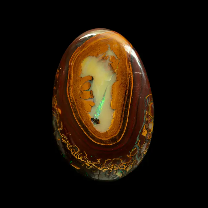 Natural Australian opal from Koroit mines, flat oval cabochon in 43.4 carat medallion with an ornate outline, contrasting annular lines and opalized center with green through-shine