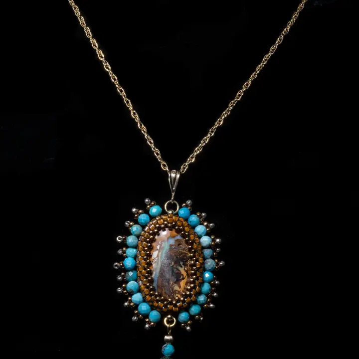 Natural Australian Koroit opal cabochon (14.7cts). Iridescent blue on a caramel matrix with lemon-yellow interlacing, it is set in a peyote weave with Miyuki Délicas glass beads, seed beads and round Turquoise beads. Rope link chain, bélière and clasp in 14k gold filled (rolled gold 585/1000). Necklace length 413 mm.   