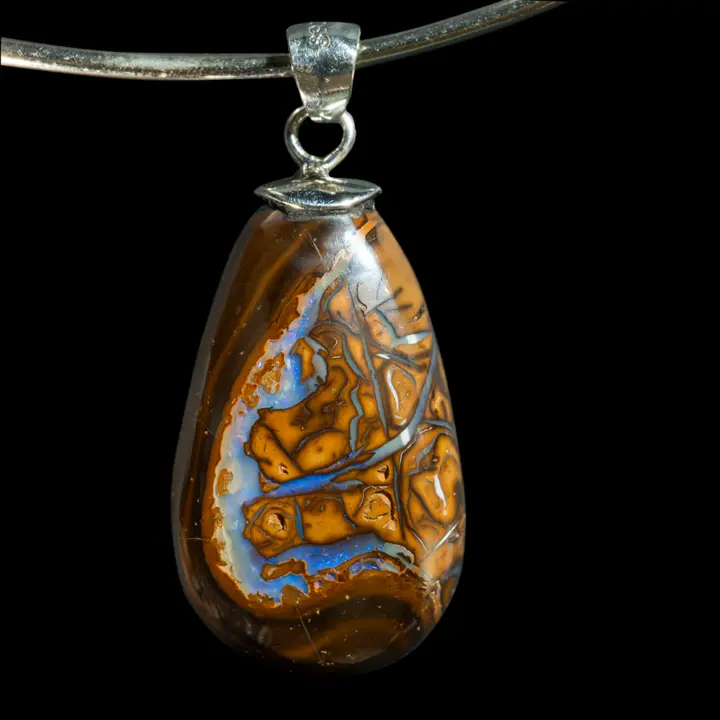 Natural Australian opal from the Koroit mines mounted in a 925 silver pendant; 19-carat opal teardrop with yellow ochre matrix traversed by connected channels and curves of brilliant blue-grey and blue.