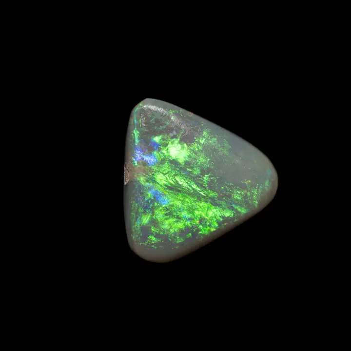 Natural Australian opal from the Lithning Ridge mines, 1.3 carat triangle shape polished on a dark matrix face, the dominant iridescence is luminous green with blue and violet flashes.